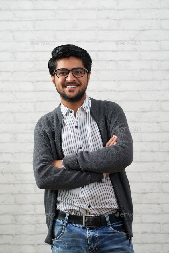 Portrait of confident handsome Indian man smiling and looking at camera